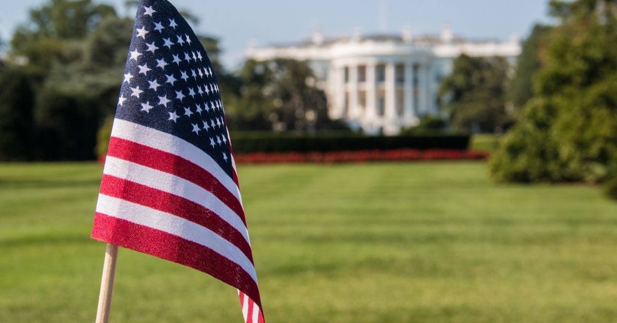 Stock image of an American flag with the White House in the background in Washington, D.C.