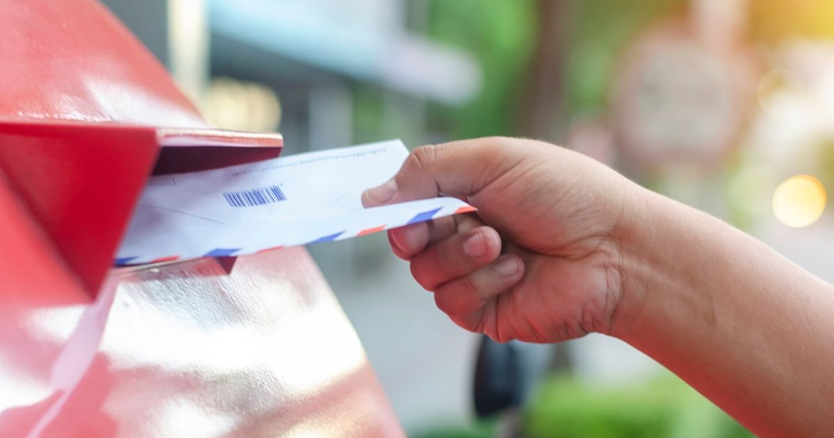 A voter deposits a ballot in a mailbox in this stock image.