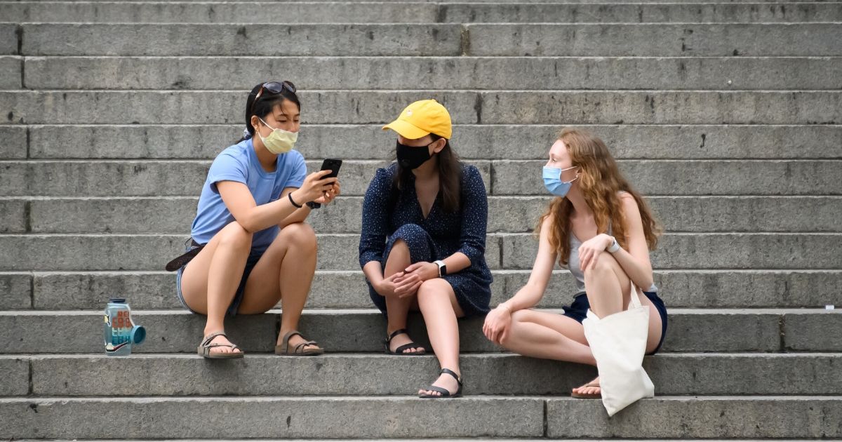 Young women wearing protective face masks sit on the steps of the Metropolitan Museum of Art in New York on May 30, 2020.
