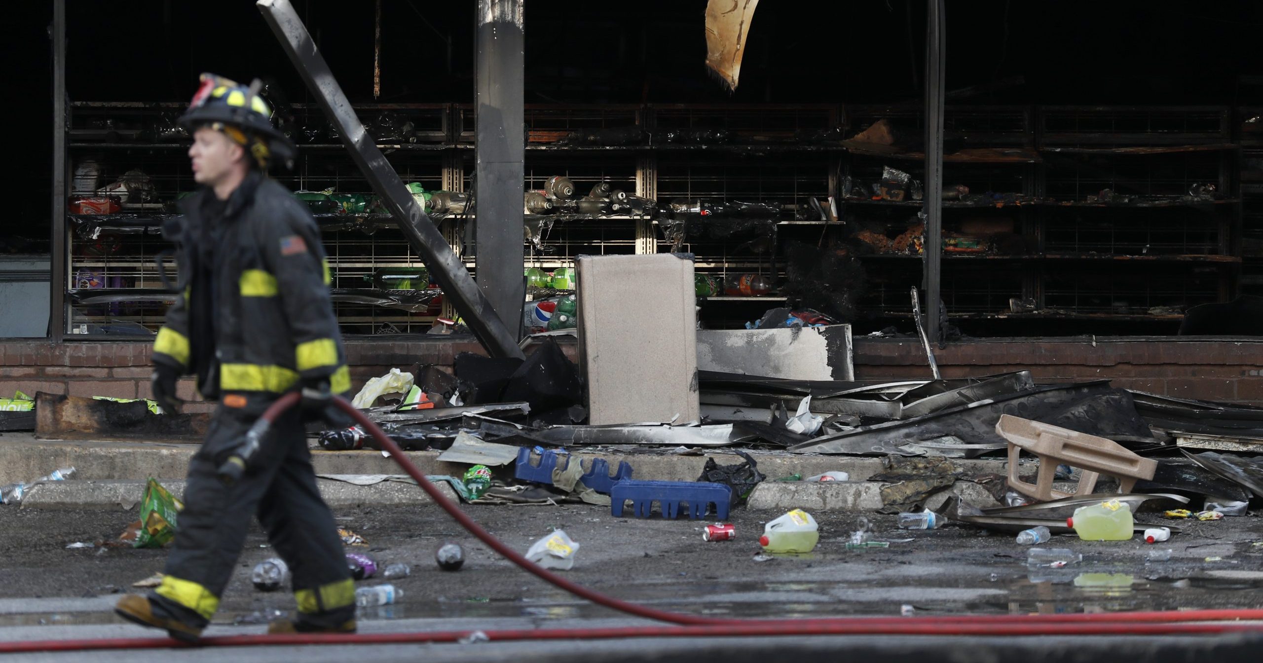 A member of the St. Louis Fire Department wraps up his work outside a vandalized and burned convenience store on Tuesday, June 2, 2020, in St. Louis. On Monday night people were seen removing items from the store before the building went up in flames after a large peaceful protest of the death of George Floyd had ended.