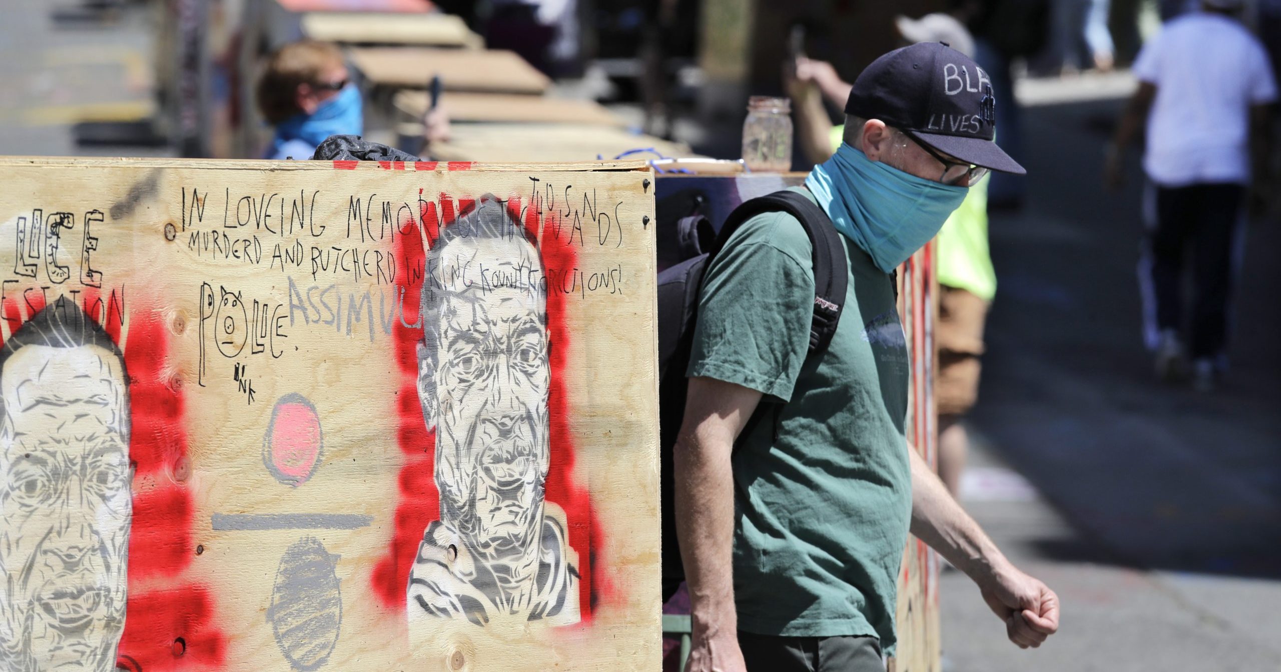 A man walks between barricades blocking a street adjacent to a closed police precinct on June 18, 2020, in Seattle, in what has been named the Capitol Hill Occupied Protest zone. Police pulled back from several blocks of the city's Capitol Hill neighborhood earlier this month after clashes with rioters.