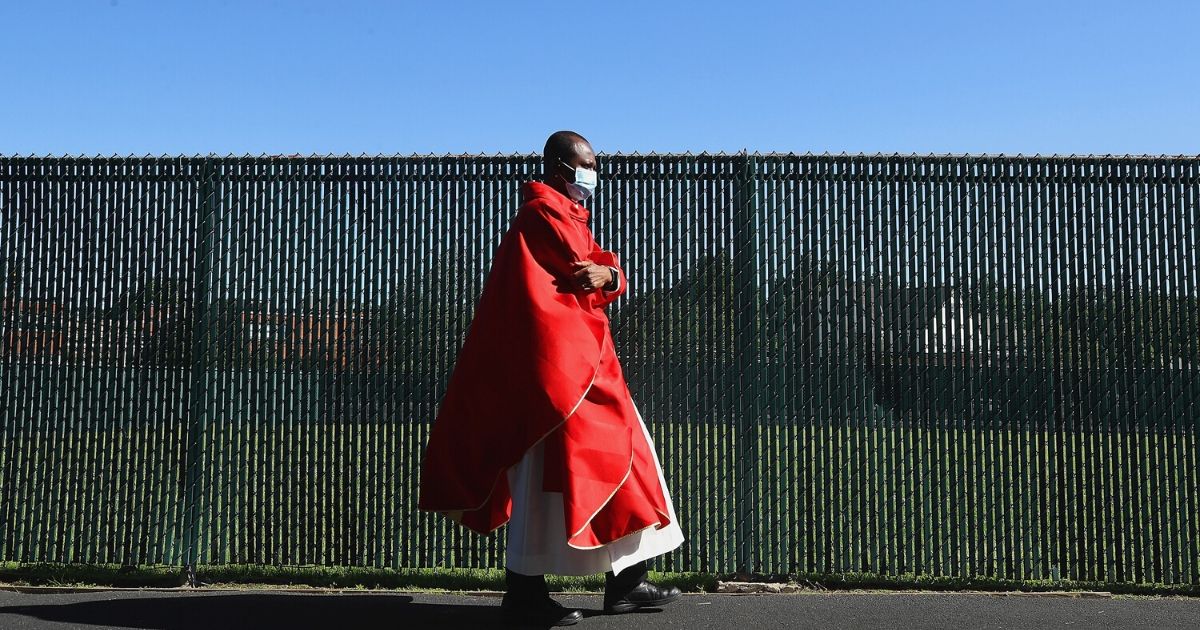 Father Bright Appiagypi-Podkye prepares for Sunday morning mass in the parking lot at the Parish of Saint Agnes Cathedral on May 31, 2020, in Rockville Centre, New York. New York state regulations require that attendees remain in their cars during mass as the parish remains mostly closed due to the coronavirus pandemic.