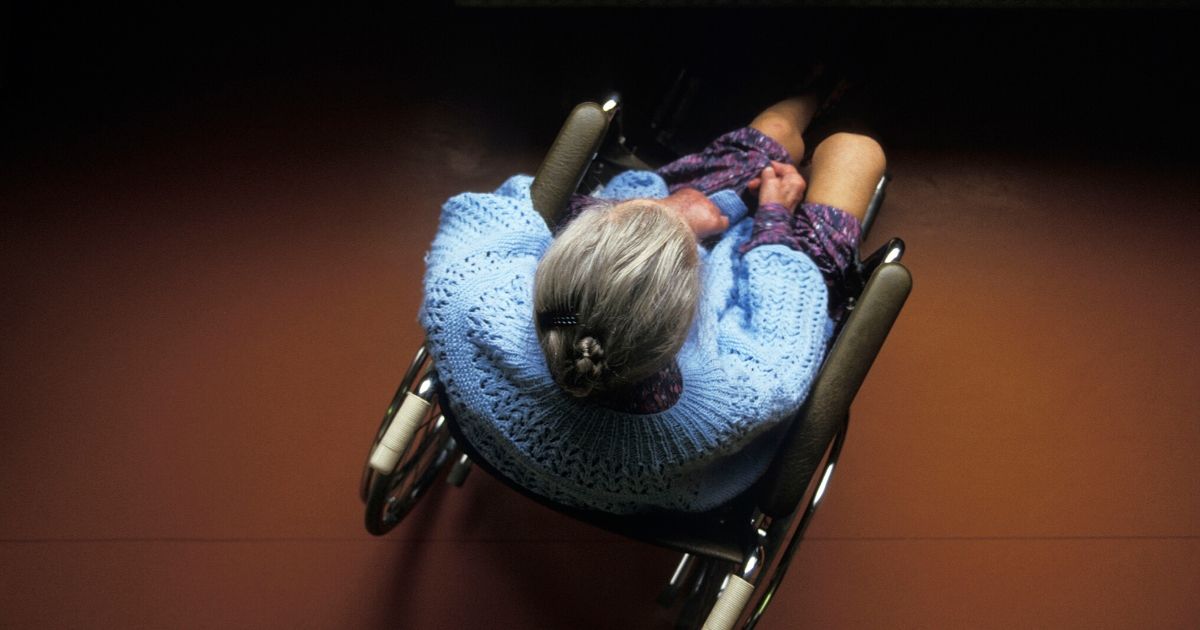 An elderly woman sits in a wheelchair.