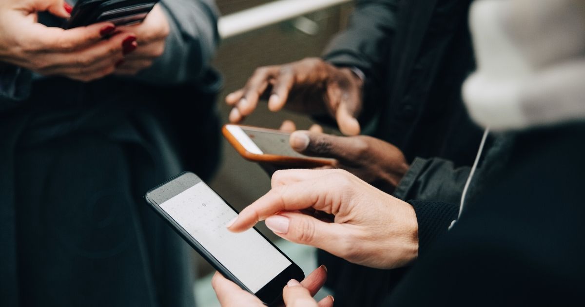 A group of people uses cell phones in the above stock image.