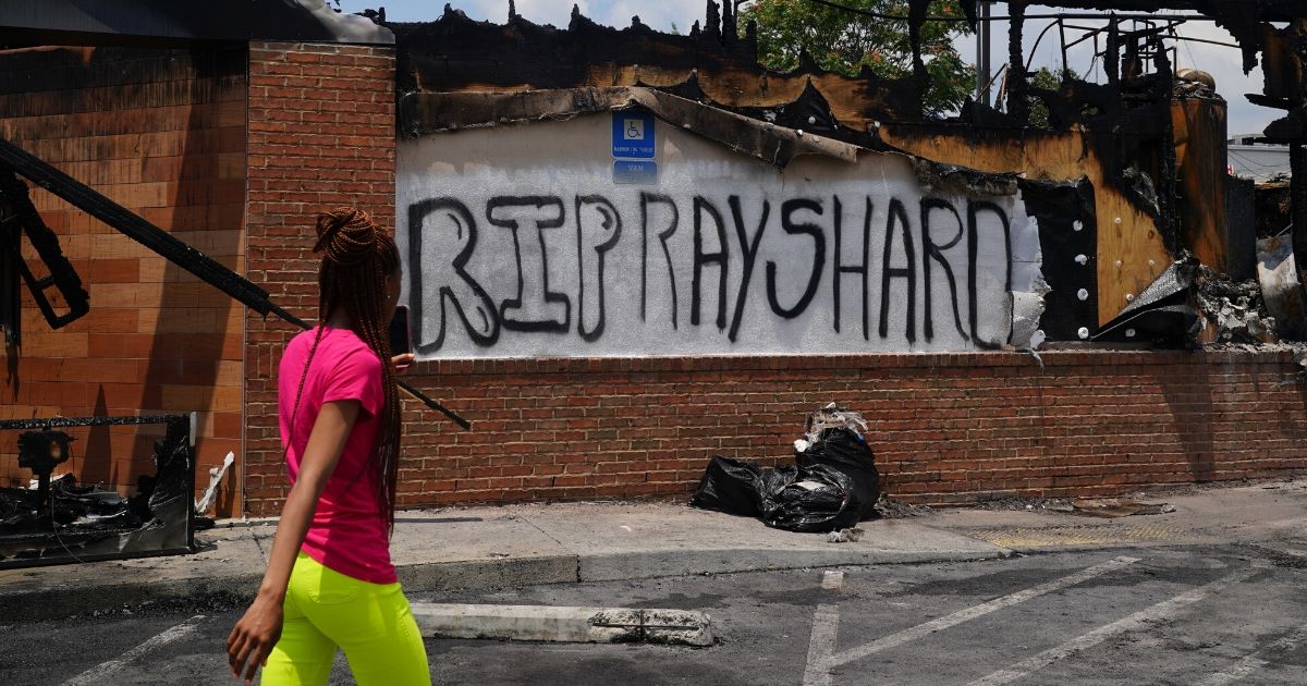 A woman uses her cell phone to document the damage to a burned Wendy's restaurant following the police shooting of Rayshard Brooks in the restaurant parking lot on June 14, 2020, in Atlanta. The restaurant where 27-year-old Brooks was killed was set on fire June 13, 2020.