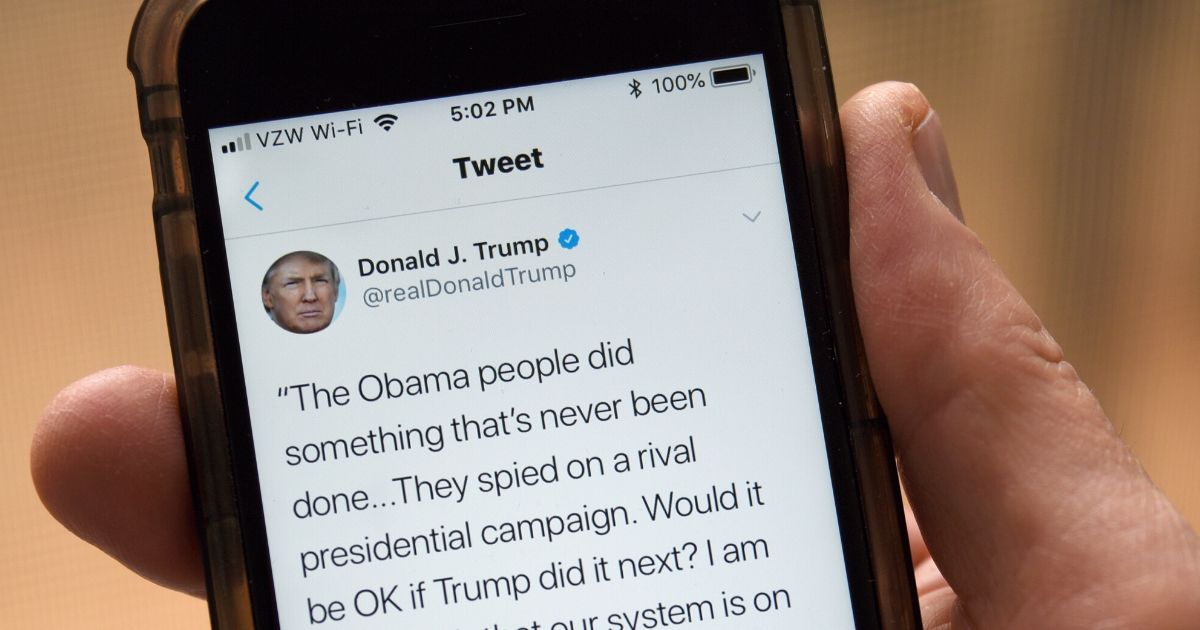 A man uses his smartphone to read a tweet from Fox News conservative political commentator Tucker Carlson retweeted by Donald Trump which accuses President Obama of spying on the Trump presidential campaign. (