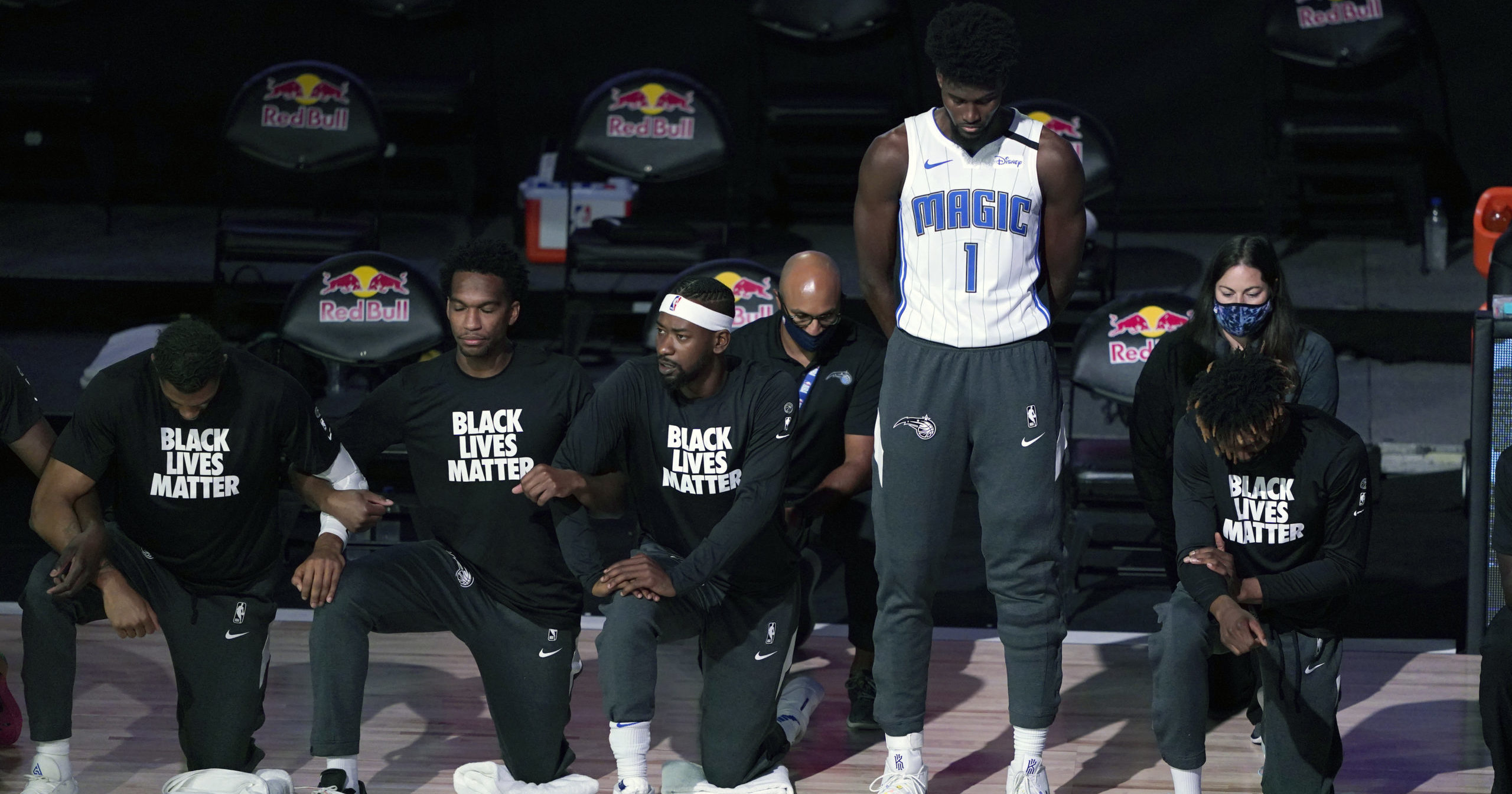 The Orlando Magic's Jonathan Isaac stands as others kneel during the national anthem before the start of an NBA basketball game between the Brooklyn Nets and the Orlando Magic on July 31, 2020, in Lake Buena Vista, Florida.