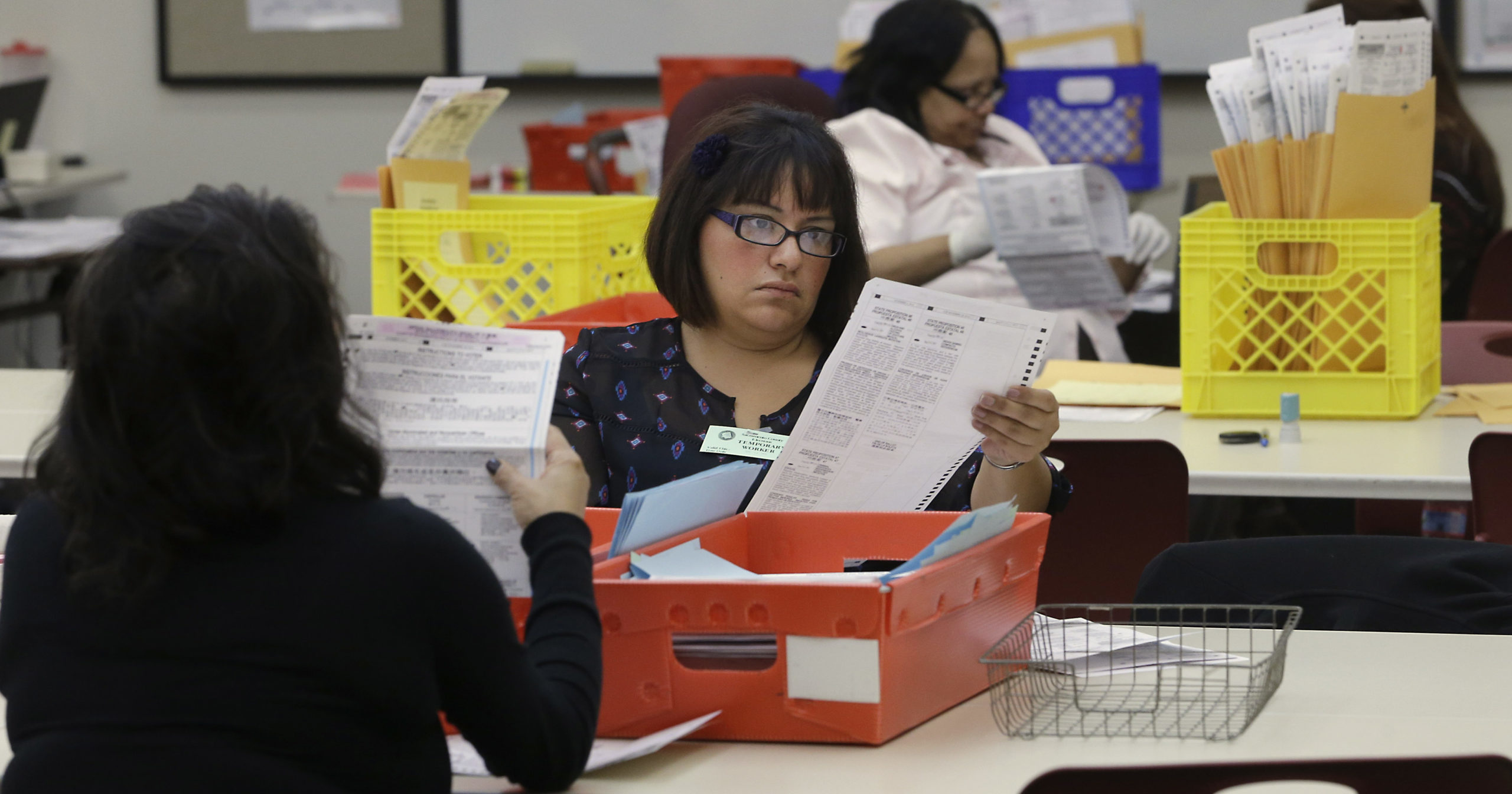 Lydia Harris, a temporary worker, looks over a mail-in ballot before it is sent to be counted Nov. 12, 2014, in Sacramento, California.