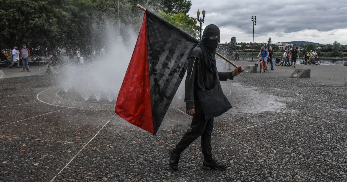 A member of Antifa walks pass a fountain in Portland, OR, during a rally on Aug. 17, 2019.