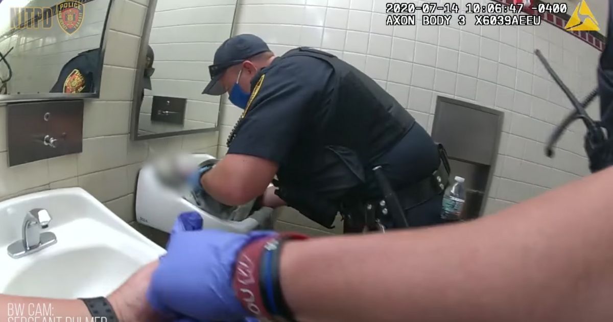 Officer Bryan Richards performing CPR on a newborn in a train station bathroom.