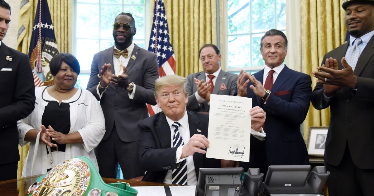 President Donald Trump holds a signed Executive Grant of Clemency for boxer John Arthur "Jack" Johnson in the Oval Office of the White House on May 24, 2018, in Washington, D.C.