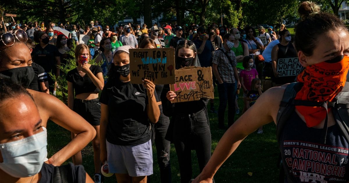 People hold signs during an anti-police protest in Minneapolis' Powderhorn Park on June 26, 2020.