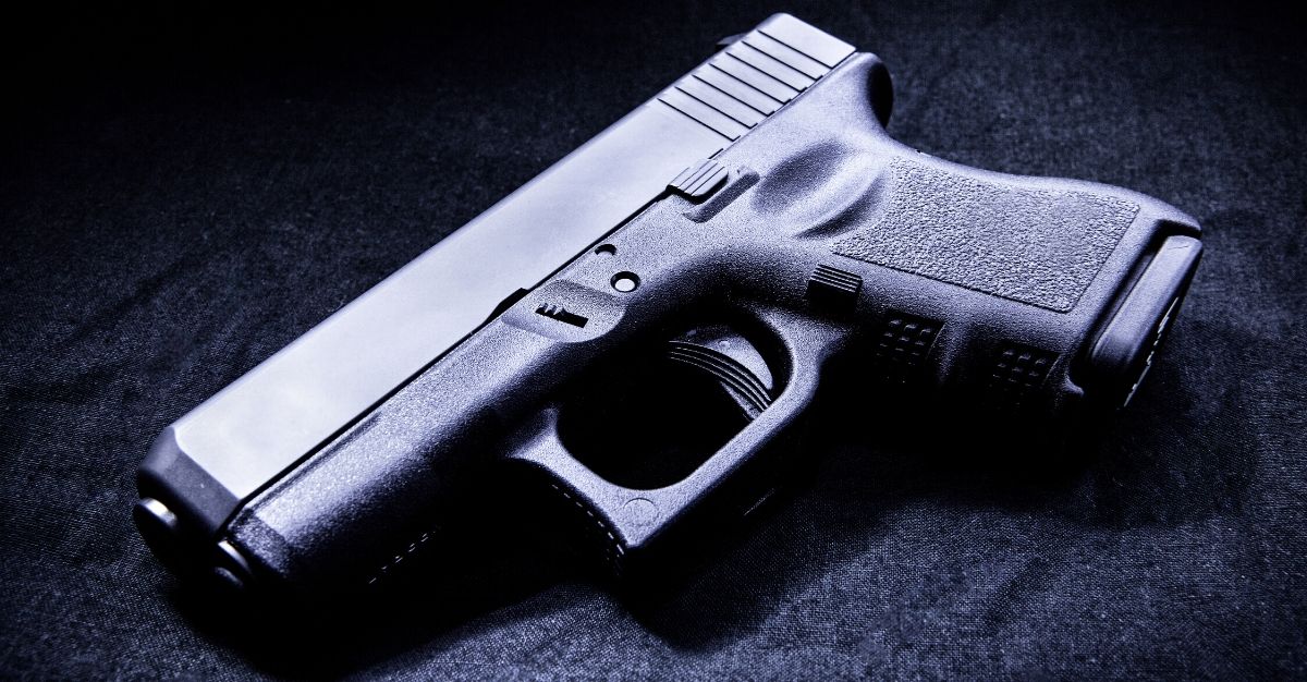 A handgun in a dark room lit by a single light source is seen in the stock image above.