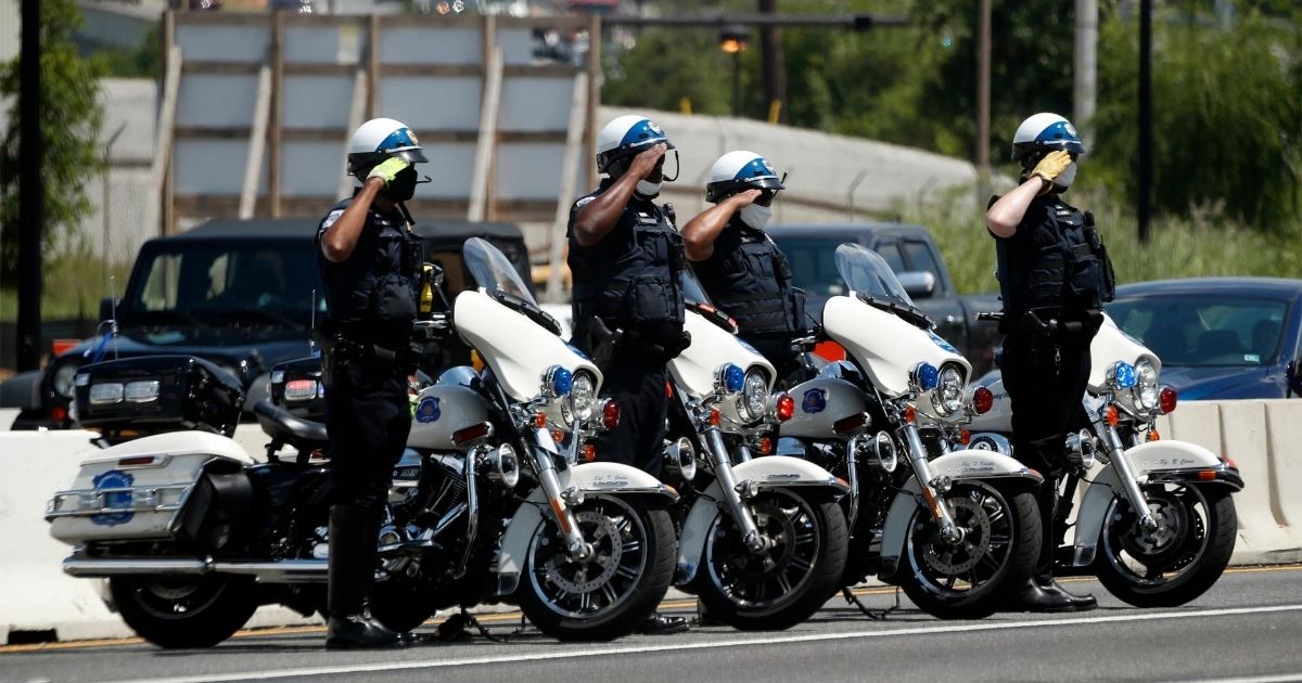 Metropolitan Police Department officers salute as a hearse with the flag-draped casket of Democratic Rep. John Lewis of Georgia passes by July 27, 2020, in Washington.