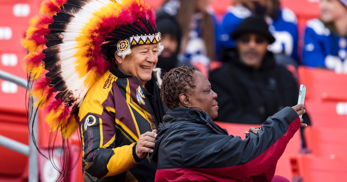 A Washington Redskins fan wearing a traditional Native American headdress poses for a photo before the team's game against the New York Giants at FedExField in Landover, Maryland, on Dec. 22, 2019.