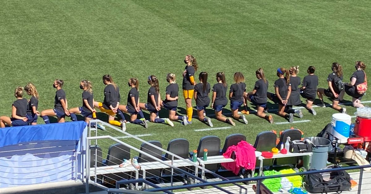 Samantha Murphy, goalkeeper for the North Carolina Courage, stands for the national anthem while her teammates kneel.