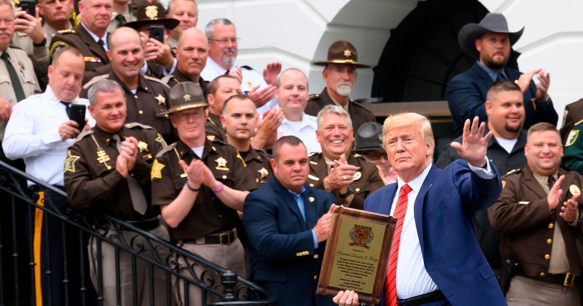 President Donald Trump waves next to a group of sheriffs after receiving an award from them at the White House in Washington on Sept. 26, 2019.