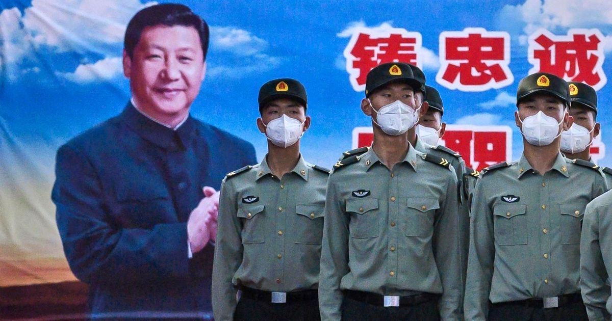 Soldiers of the People's Liberation Army's Honour Guard Battalion wear protective masks as they stand at attention in front of photo of Chinese President Xi Jinping at their barracks outside the Forbidden City near Tiananmen Square on May 20, 2020, in Beijing, China.