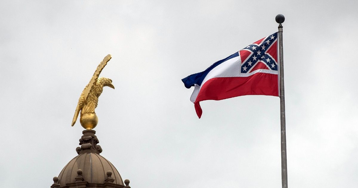 The now-retired flag state flag of Mississippi, bearing the Confederate battle standard, flies over the state Capitol building in Jackson in June.