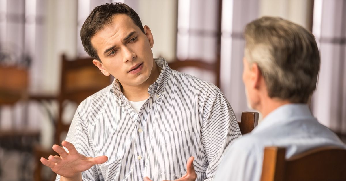 Two men engage in a discussion at a cafe table.