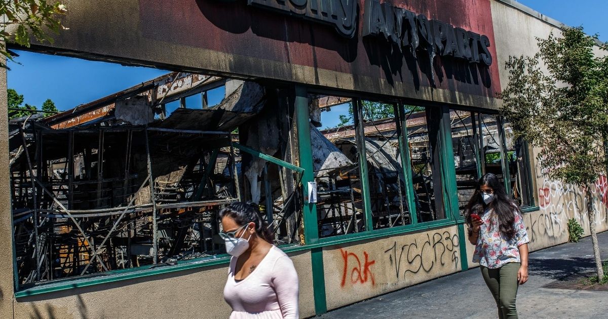 Pedestrians pass the burned out shell of an O'Reilly Autoparts store in Minneapolis on June 3, 2020.