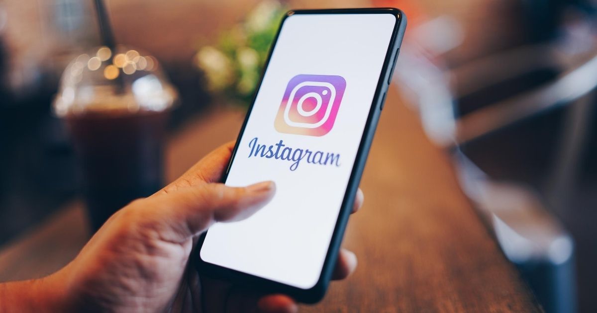 A stock image of a man holding a phone with Instagram on the screen is pictured above.