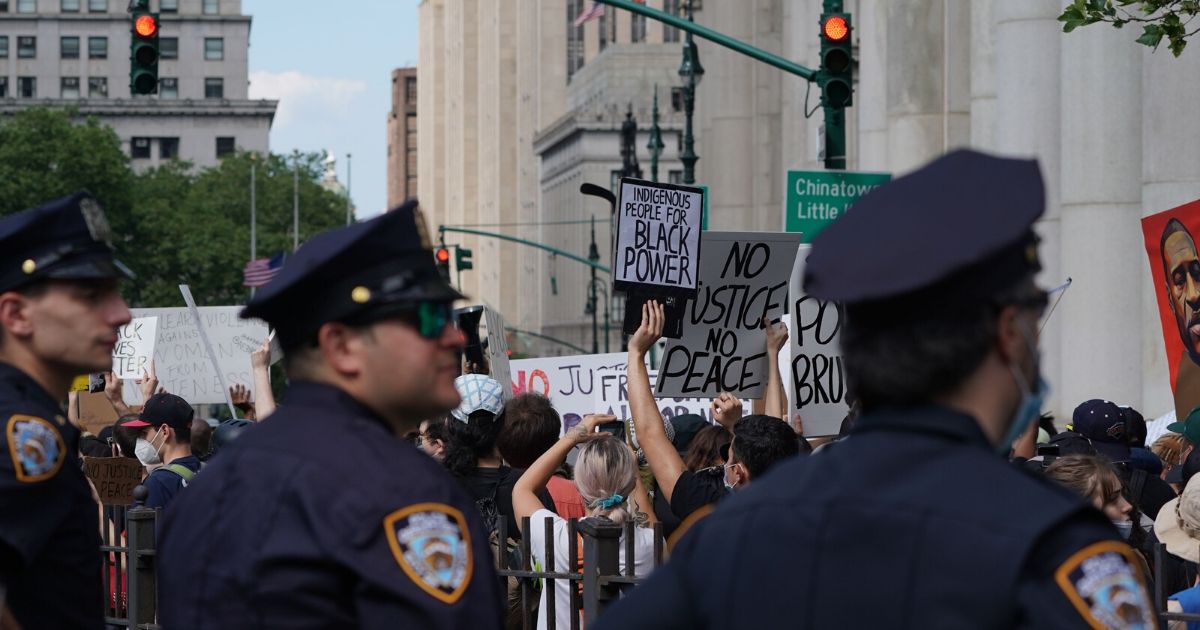 New York City police officers look on as protesters march into Manhattan from the Brooklyn Bridge on June 19, 2020, over the death of George Floyd in Minneapolis police custody on May 25.