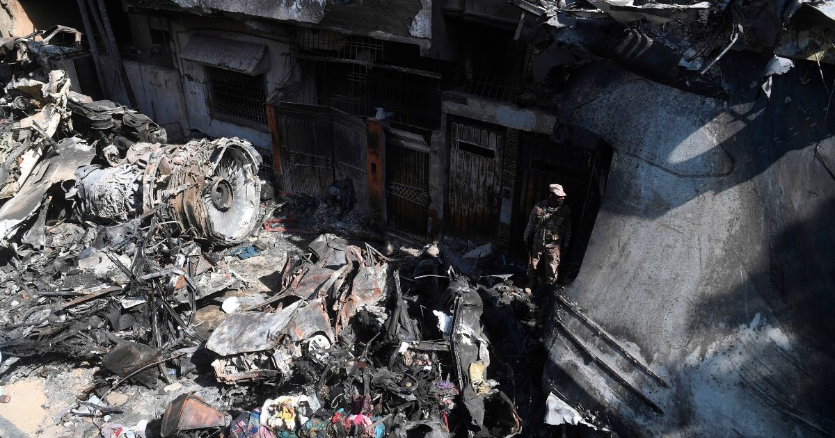 A security personnel member stands guard beside the wreckage of a plane at the site after a Pakistan International Airlines aircraft crashed in a residential area in Karachi just two days earlier, on May 22, 2020.