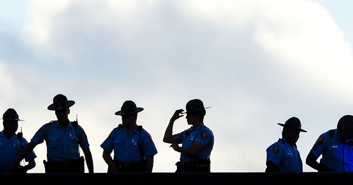 Police stand guard on a bridge as protesters block the road next to a burned Wendy's restaurant on the fourth day following Rayshard Brooks' death in the restaurant parking lot on June 16, 2020, in Atlanta, Georgia.