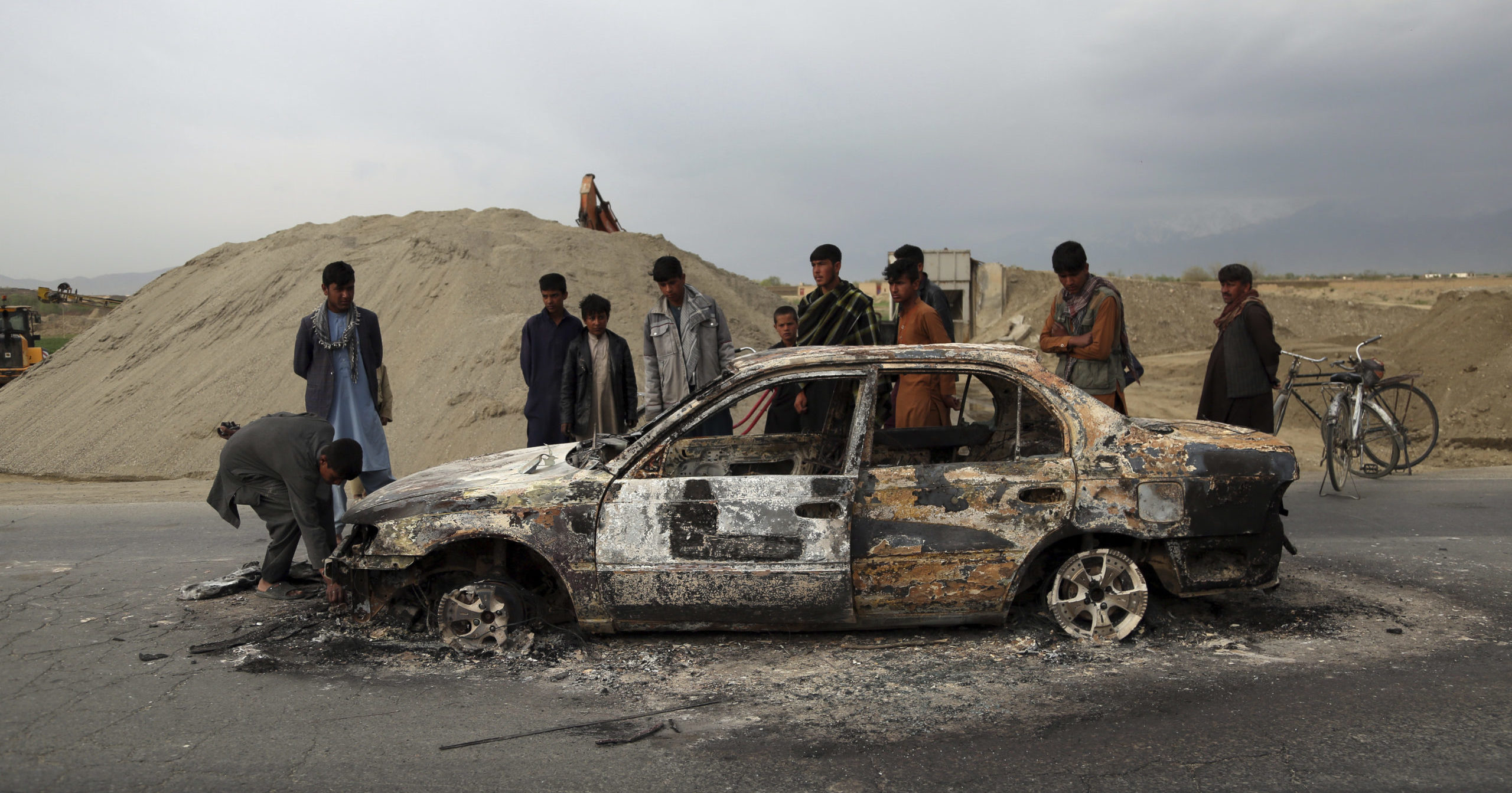 In this April 9, 2019, file photo, Afghans watch a vehicle burn after being shot by U.S. forces following a Taliban attack near the Bagram Air Base, north of Kabul, Afghanistan.