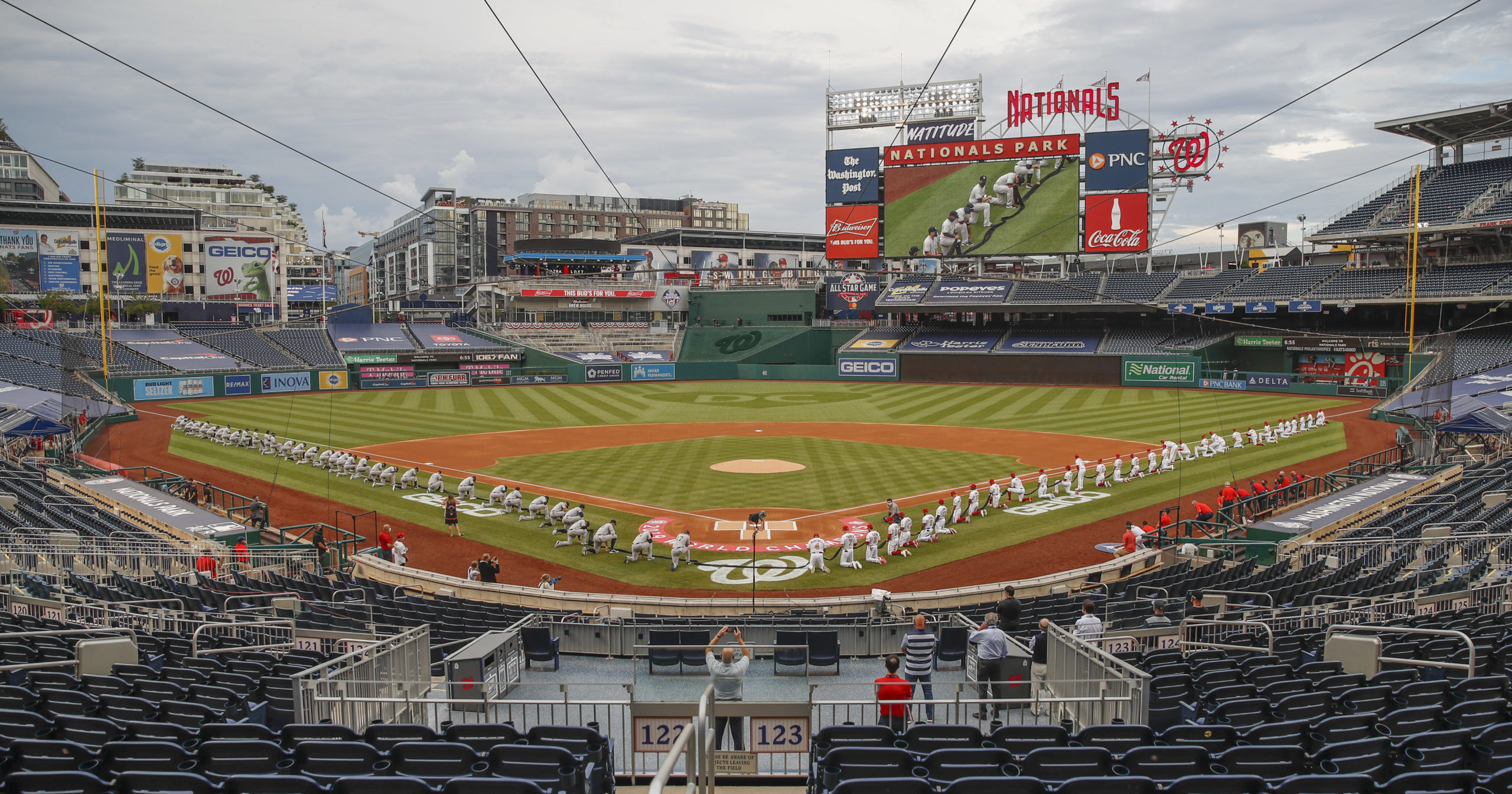 The New York Yankees and the Washington Nationals kneel while holding a black ribbon to honor Black Lives Matter before playing an opening day baseball game at Nationals Park on July 23, 2020, in Washington.