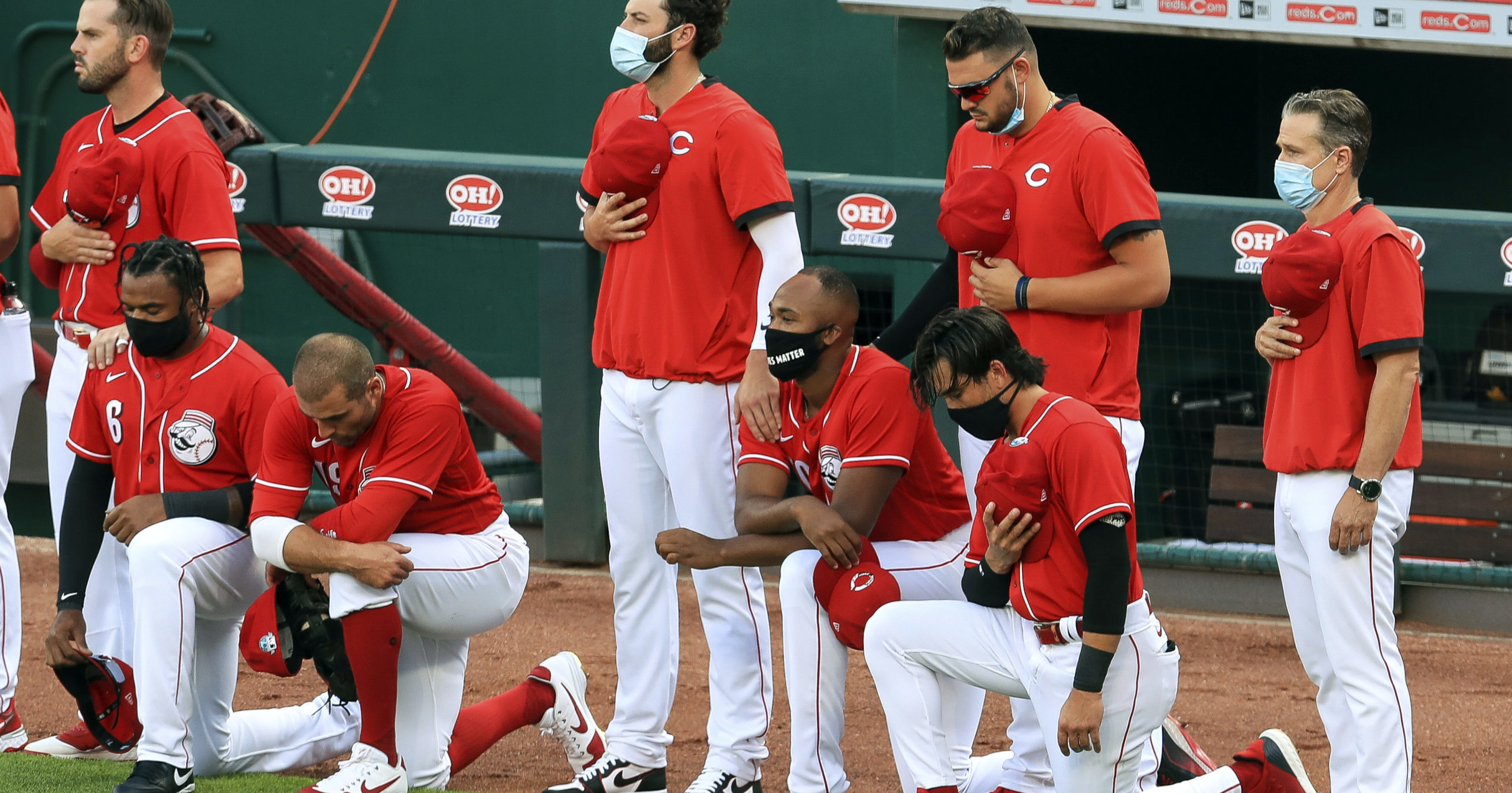 Cincinnati Reds' Phillip Ervin, left, Joey Votto, left middle, Amir Garrett, middle, and Alex Blandino, right, kneel during the national anthem prior to an exhibition baseball game against the Detroit Tigers at Great American Ballpark in Cincinnati on July 21, 2020.