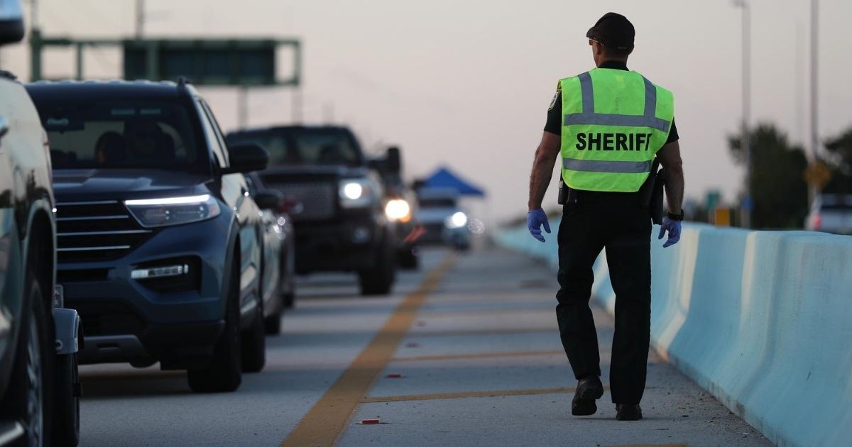 A police officer mans a checkpoint on U.S. 1 leading into the Florida Keys on March 27, 2020, in Florida City, Florida.