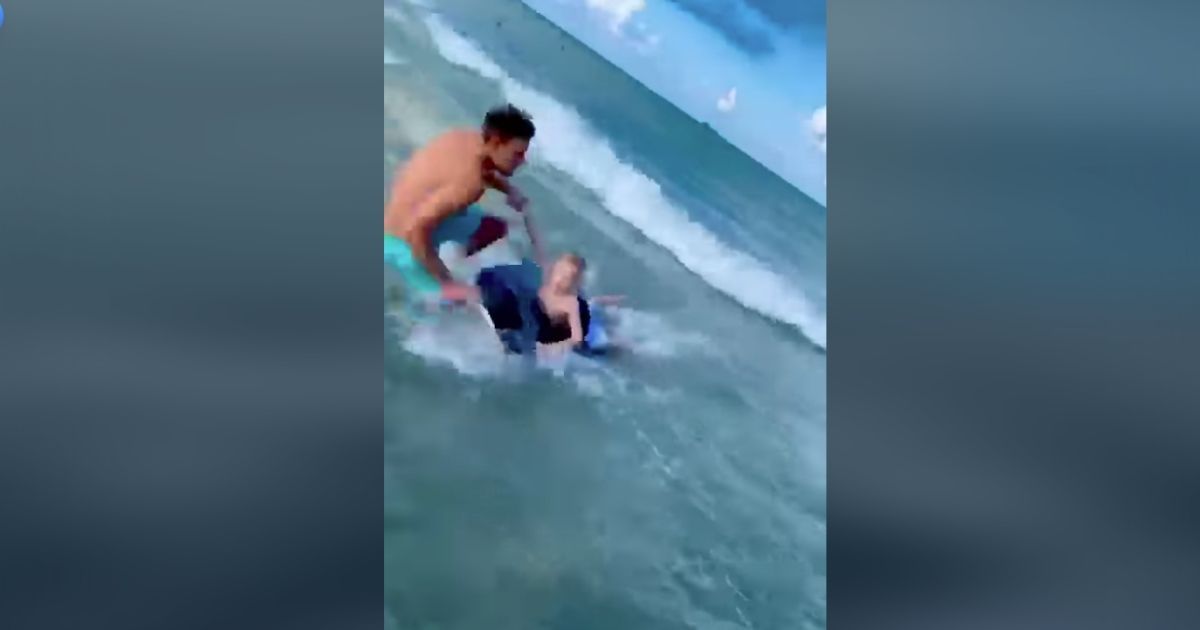 Officer Kosicki pulling a boy out of the water and saving him from a shark attack.