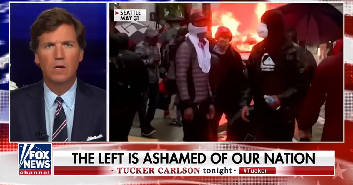 Fox News host Tucker Carlson shares a screen with a still image from a fire burning at a riot.