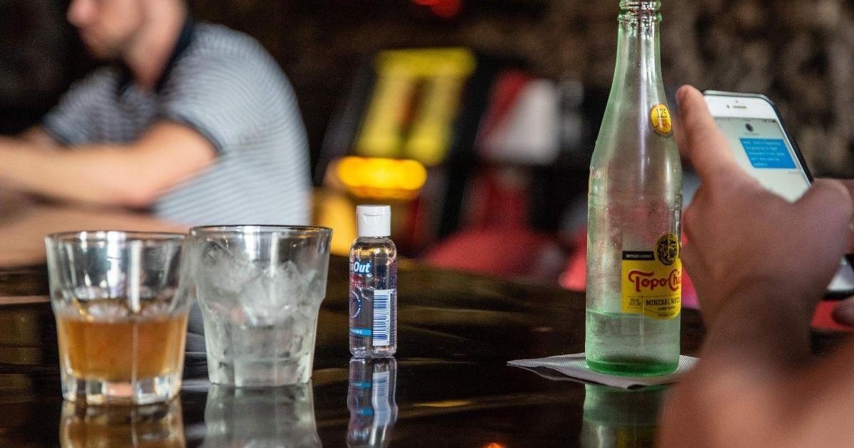 A bottle of hand sanitizer sits on a bar next to drinks at a restaurant in Austin, Texas, on June 26, 2020.