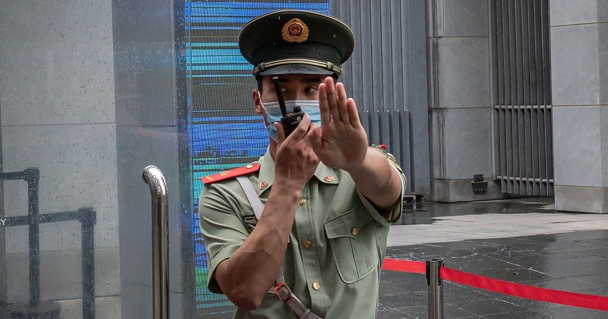 A Chinese paramilitary police officer gestures and speaks over his two-way radio whlie standing at the entrance gate of the Australian embassy in Beijing on July 9, 2020.