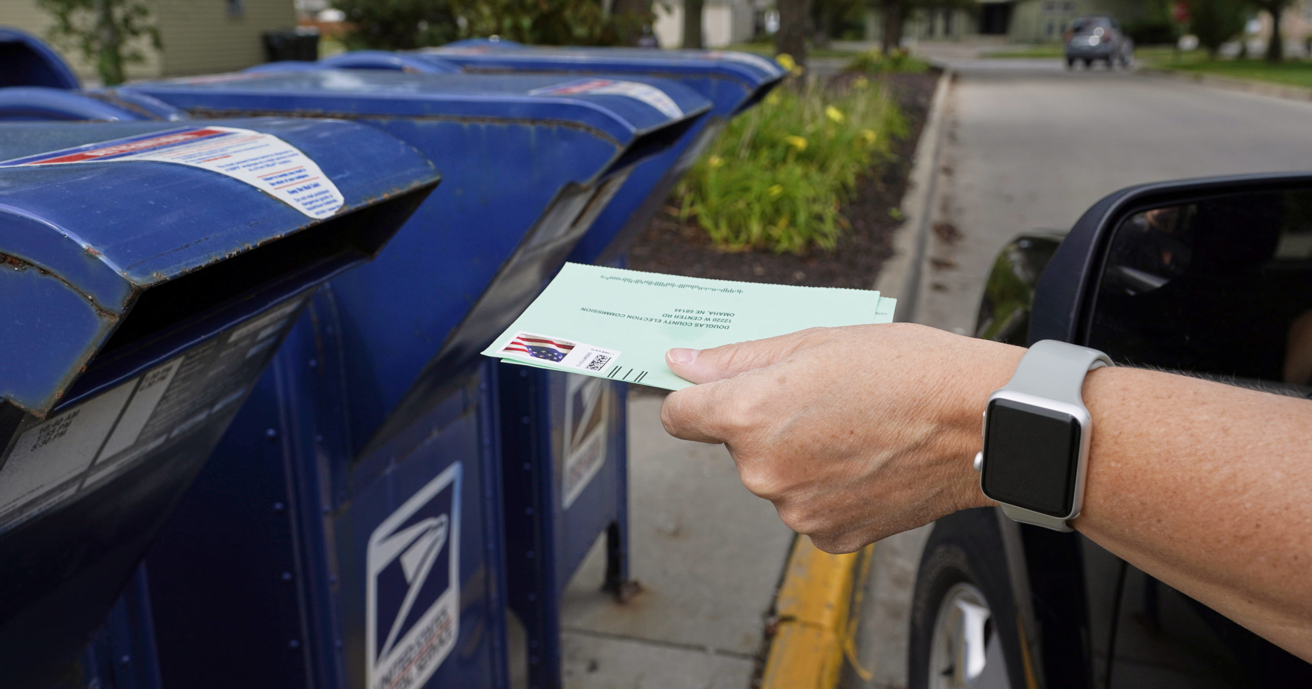 In this Aug. 18, 2020, file photo, a person drops applications for mail-in ballots into a mailbox in Omaha, Nebraska.