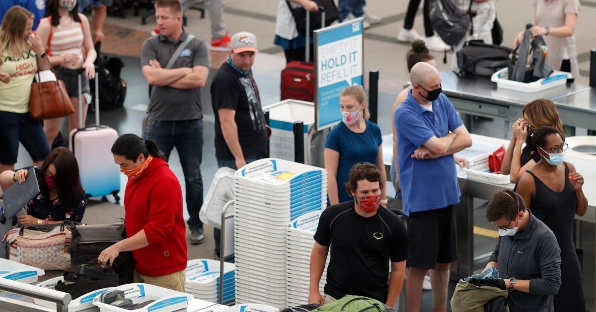 Travelers wear protective masks while moving through a security checkpoint at Denver International Airport on June 22, 2020.