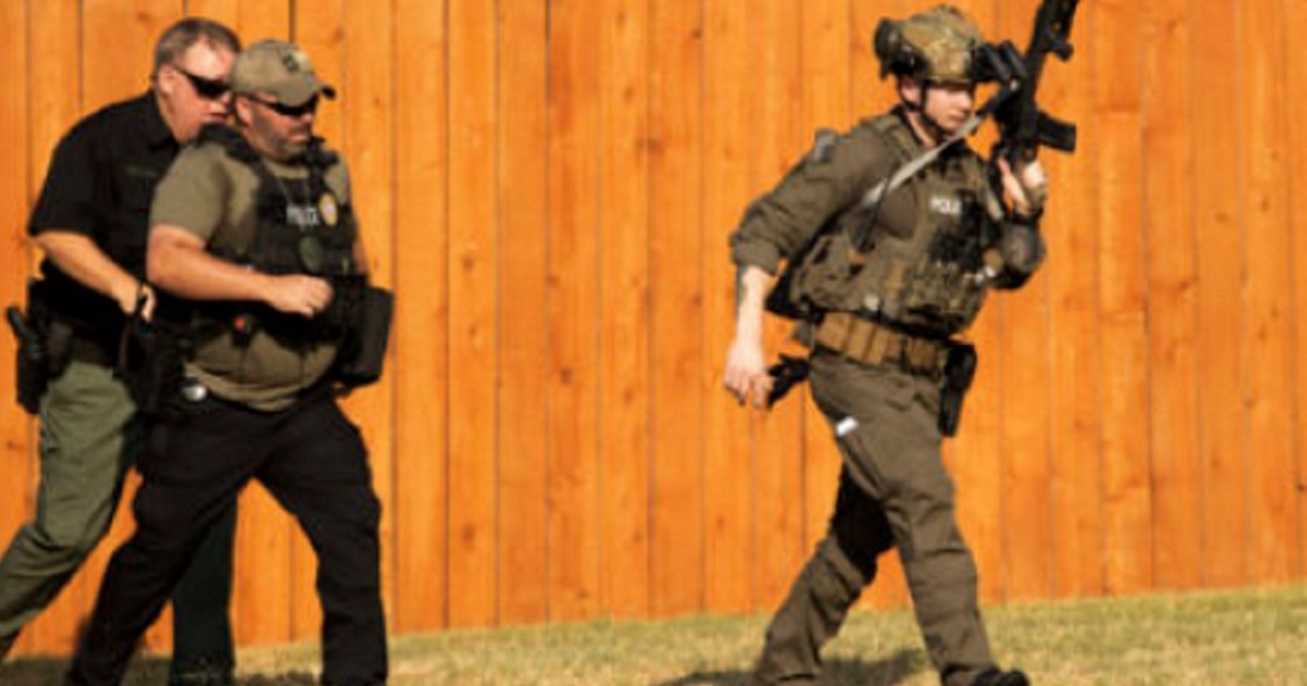 Police officers take up their stations near a house in Cedar Park, Texas, on Sunday during a hostage situation that left three officers wounded.