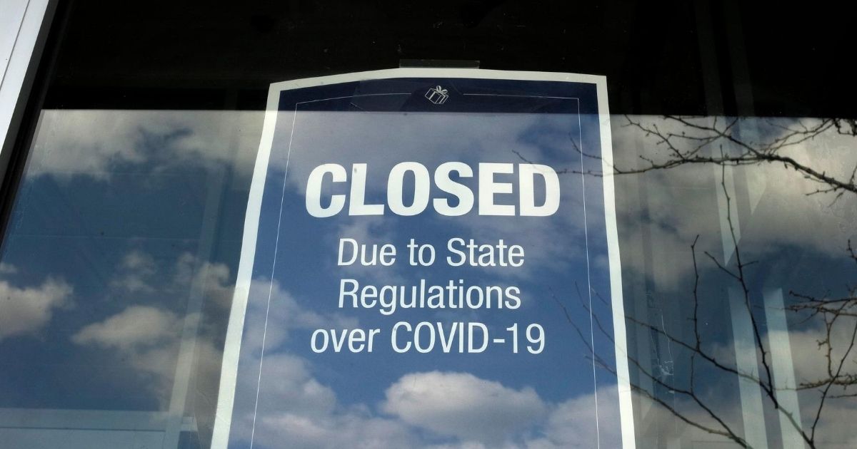 In this April 22, 2020, photo, a closed sign is posted in the window of a store because of the coronavirus at an outdoor mall, in Dedham, Massachusetts.