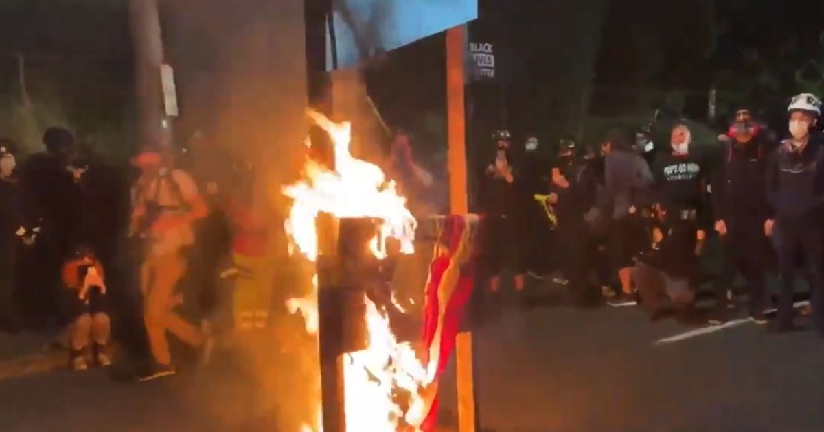 An American flag burns on a guillotine in Portland, Oregon.