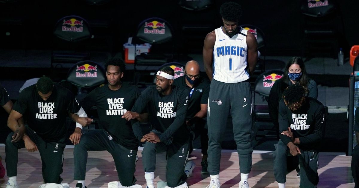 Orlando Magic player Jonathan Isaac (1) stands as others kneel before the start of an NBA basketball game between the Brooklyn Nets and the Orlando Magic on July 31, 2020, in Lake Buena Vista, Florida.