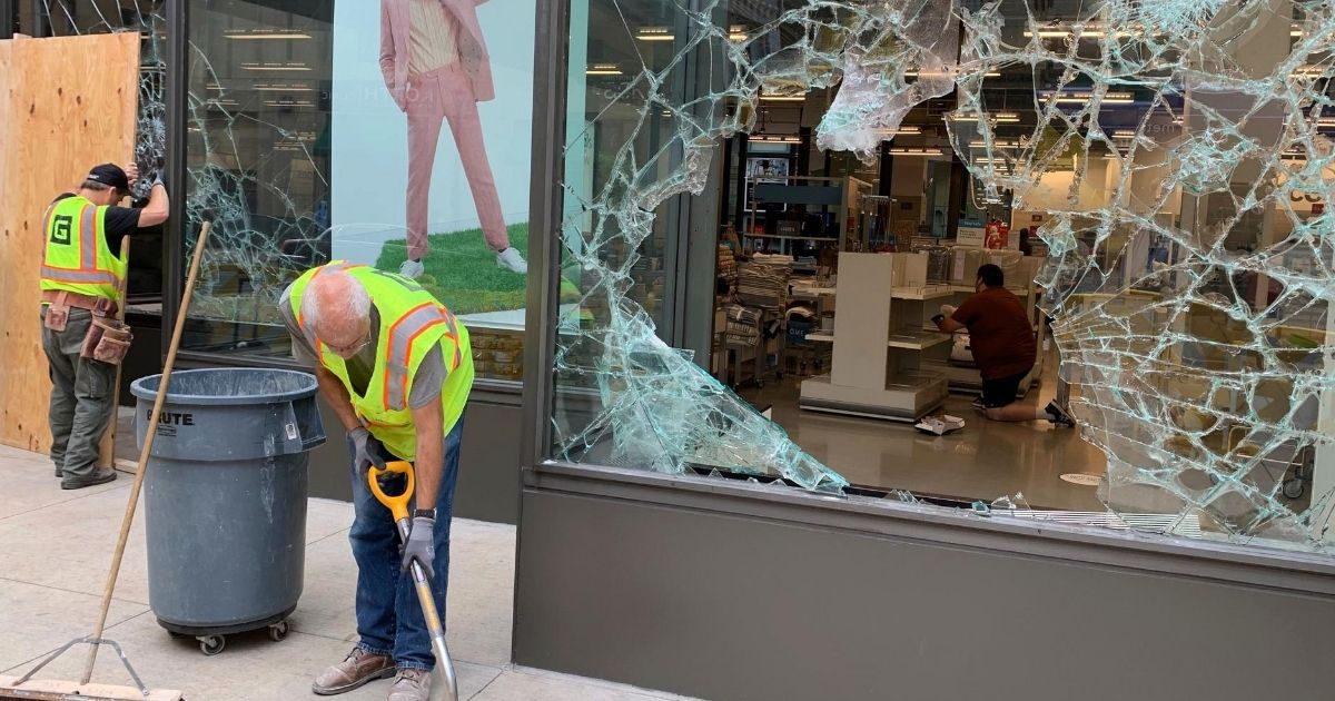 A worker shovels broken glass outside of Nordstrom Rack in downtown Minneapolis on Aug. 27, 2020.