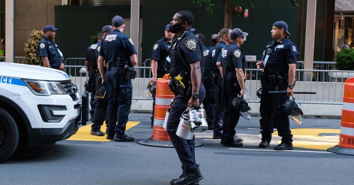 An NYPD officer carries out paint cans after a protester poured black paint on the Black Lives Matter mural outside of Trump Tower on Fifth Avenue in the Manhattan borough of New York on July 18, 2020.