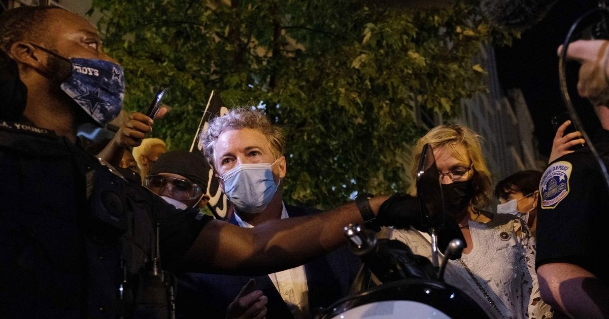 Police officers escort and guard Republican Sen. Rand Paul and his wife, Kelley, as they are surrounded by demonstrators after President Donald Trump's acceptance speech at the White House in Washington on Aug. 27, 2020.
