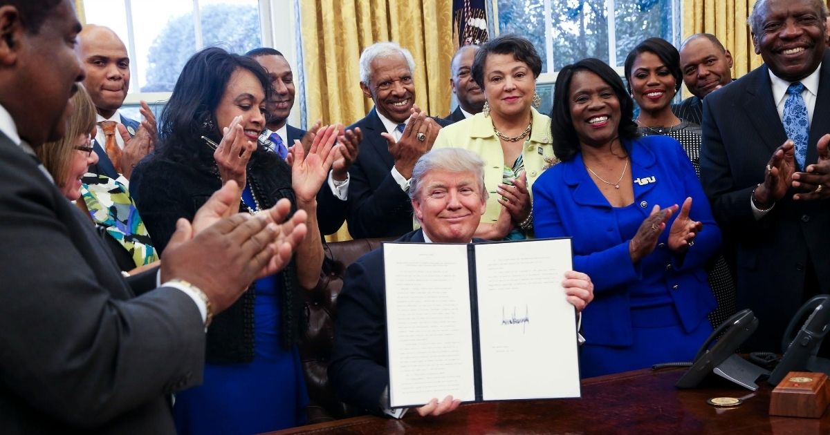 President Donald Trump holds up his signed executive order supporting black colleges and universities in the Oval Office of the White House on Feb. 28, 2017.