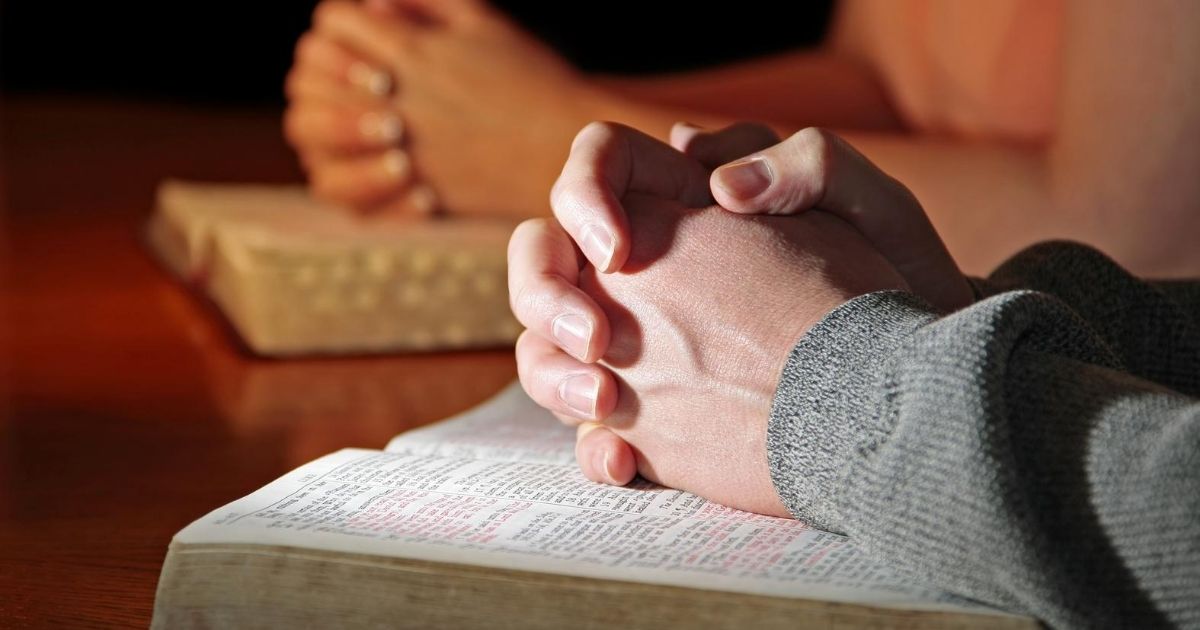 A stock image of people praying with their Bibles is pictured above.
