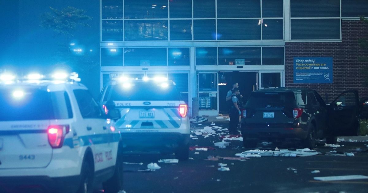 Police officers inspect a damaged Best Buy store in Chicago after parts of the city were struck by widespread looting and vandalism overnight Sunday.