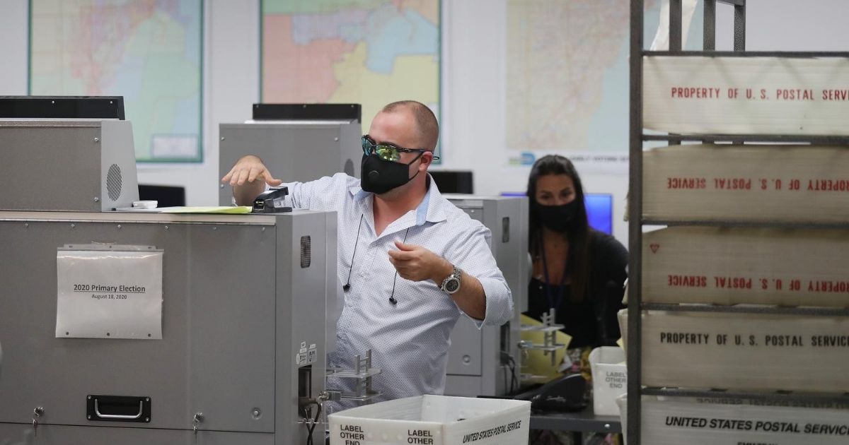 Workers at the Miami-Dade County Elections Department tabulate mail-in ballots on primary election day on Aug. 18, 2020, in Doral, Florida.